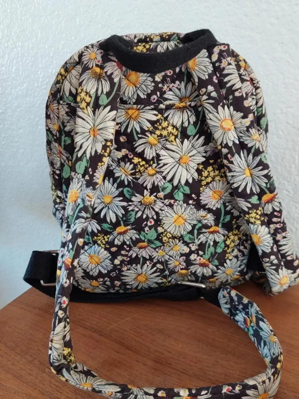 Vera Bradley Daisy Floral Backpack with white daisies and yellow centers on a da